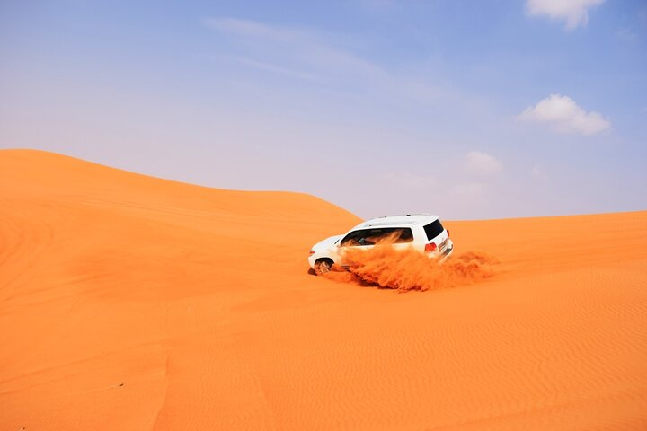 Experience the rush of dune bashing in Dubai's stunning red dunes where expert guides ensure safety while you soak in the unique desert landscape and breathtaking sunset views.